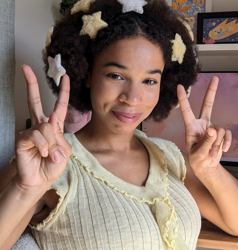 Person with star-shaped hair accessories making peace signs indoors.